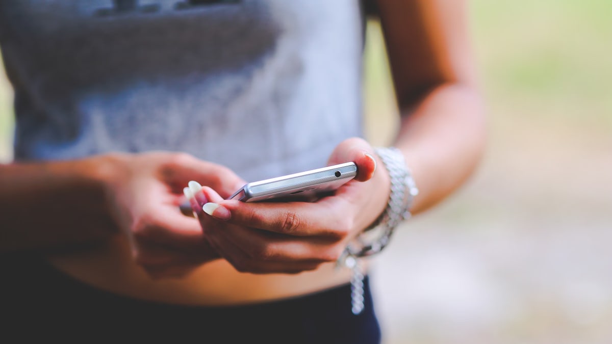 Close-up of a woman texting on a smartphone outdoors, emphasizing mobile connectivity and technology.